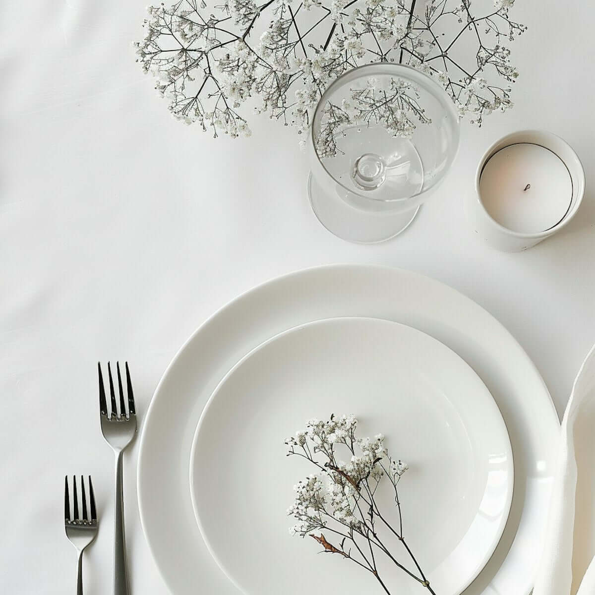 White Porcelain Kitchenware UAE elegantly set on a table with flowers and candle, showcasing simplicity and style.